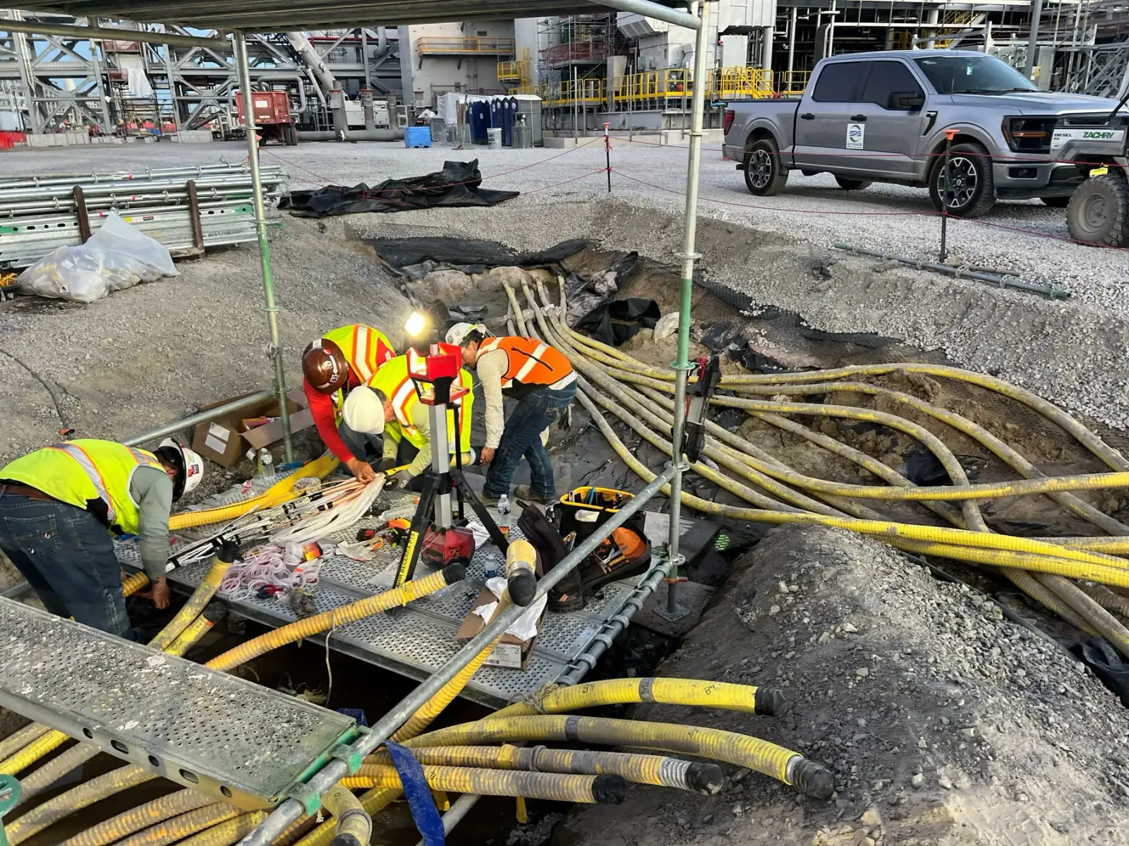 Sitewide electricians installing medium-voltage cable in an open trench on site